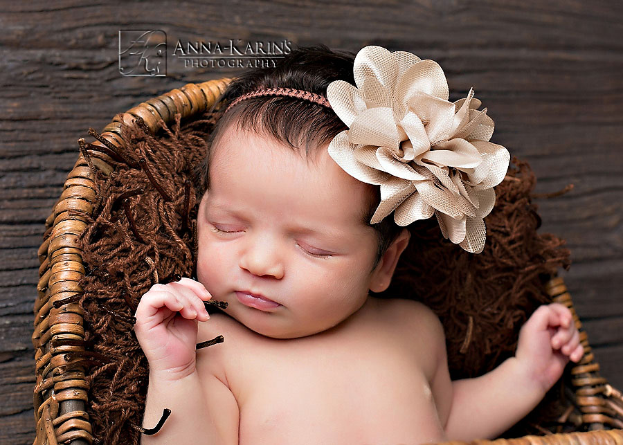 Newborn baby girl with a hair bow, sweet baby in basket