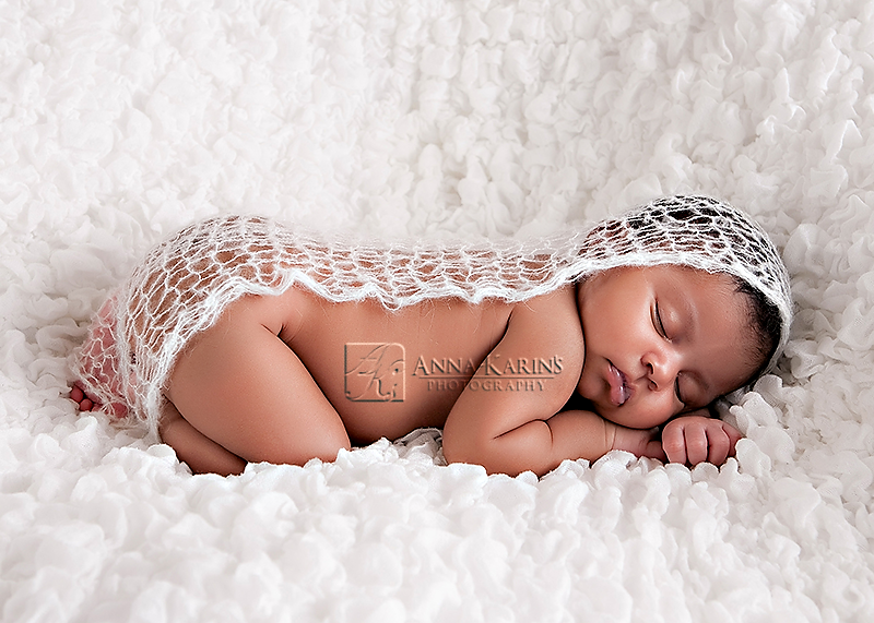 Sleepy curled up newborn baby girl, beautiful African American newborn baby girl