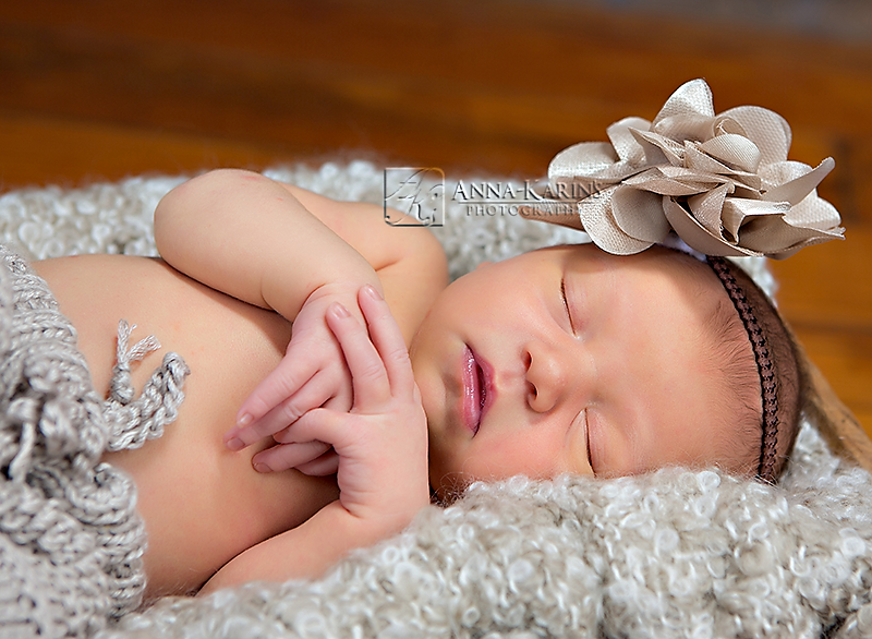 beautiful newborn baby with knitted baby pants and pretty head band in beige