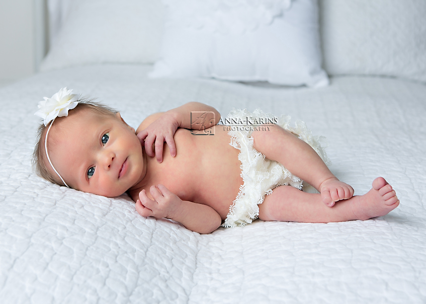 Sweet newborn baby girl with a head full of hair, newborn baby girl on white bed.
