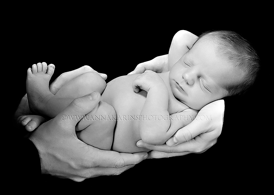 Sweet newborn baby girl in her parents arms